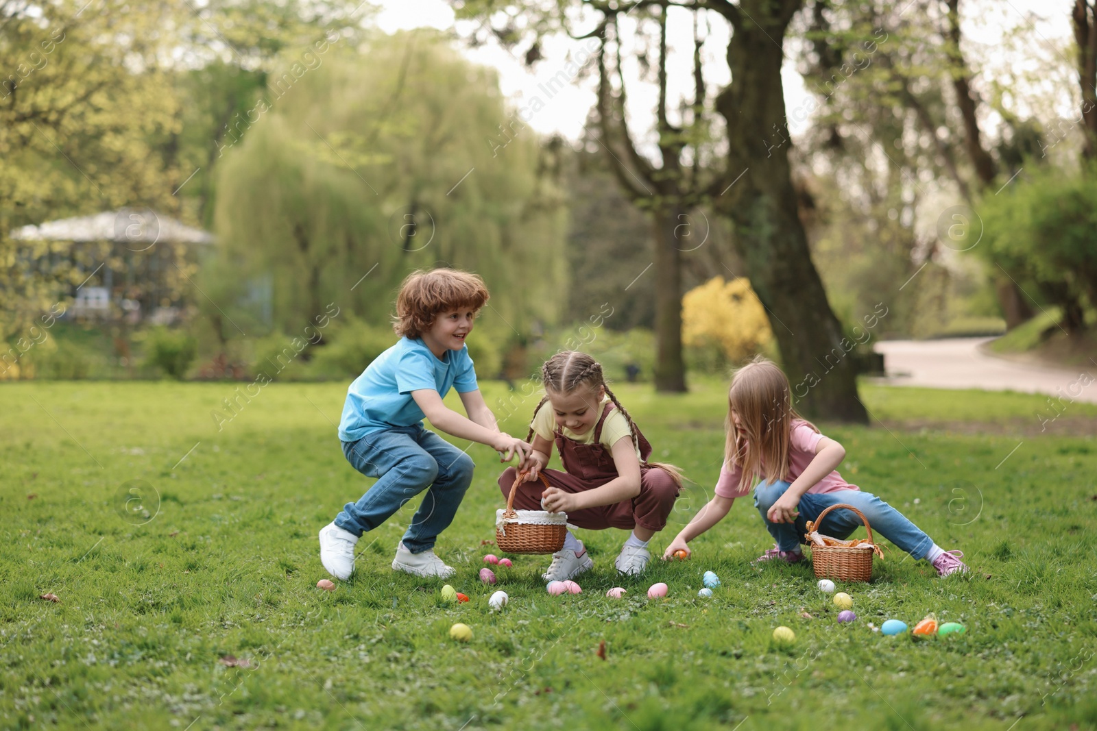 Photo of Easter celebration. Cute little children hunting eggs outdoors