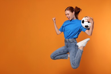 Photo of Happy fan with football ball jumping on orange background, space for text