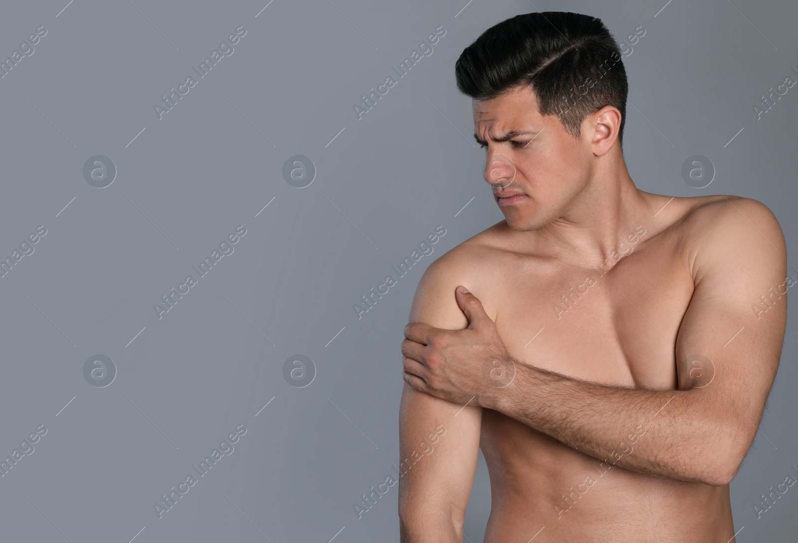 Photo of Man suffering from shoulder pain on grey background. Space for text