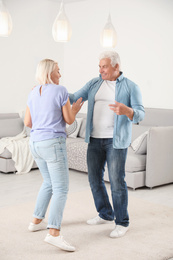 Happy mature couple dancing together in living room