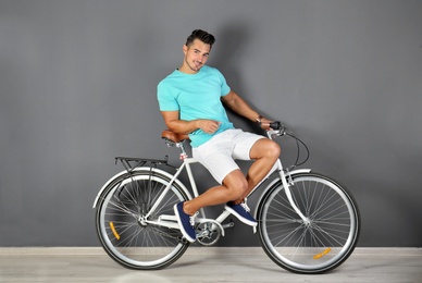 Photo of Handsome young hipster man with bicycle near color wall