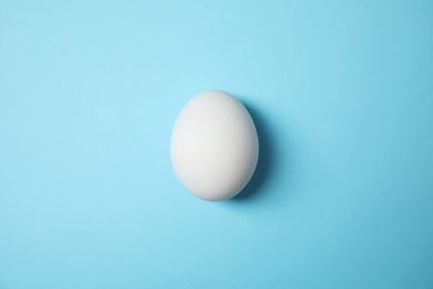 Raw chicken egg on color background, top view