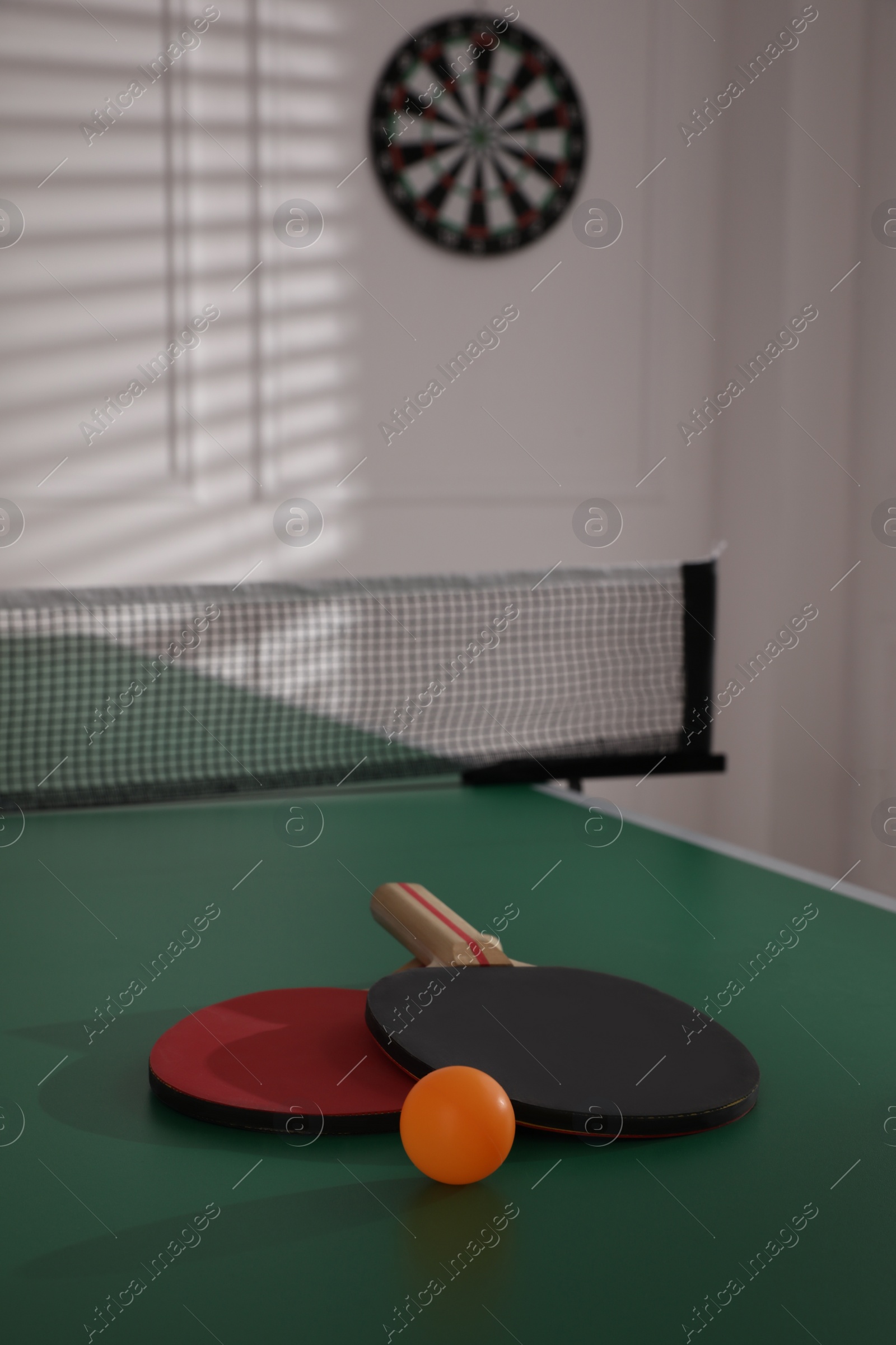 Photo of Rackets and ball on ping pong table indoors, space for text