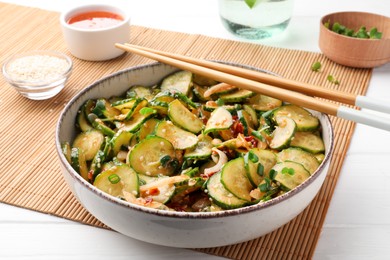 Photo of Bowl of delicious cucumber salad served on white wooden table, closeup