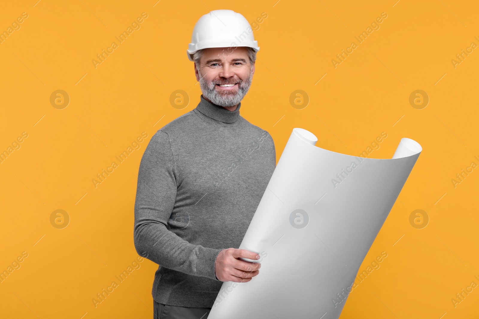 Photo of Architect in hard hat holding draft on orange background