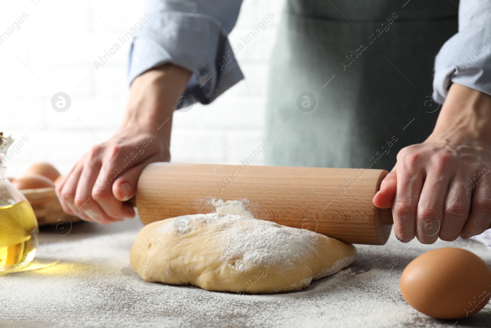 Photo of Woman rolling raw dough at table, closeup