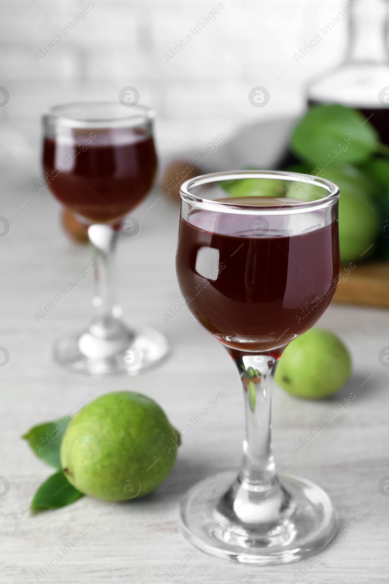 Photo of Delicious liqueur and green walnuts on wooden table