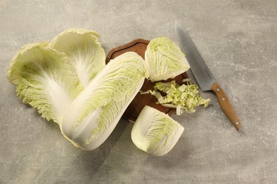 Photo of Whole and cut fresh Chinese cabbages on light grey table, flat lay