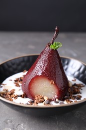 Photo of Tasty red wine poached pear with muesli and yoghurt in bowl on grey table, closeup