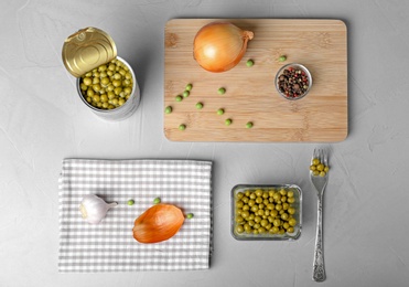 Flat lay composition with canned green peas on grey background