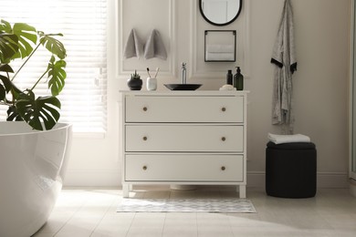 Photo of Stylish mat with pattern near chest of drawers in bathroom