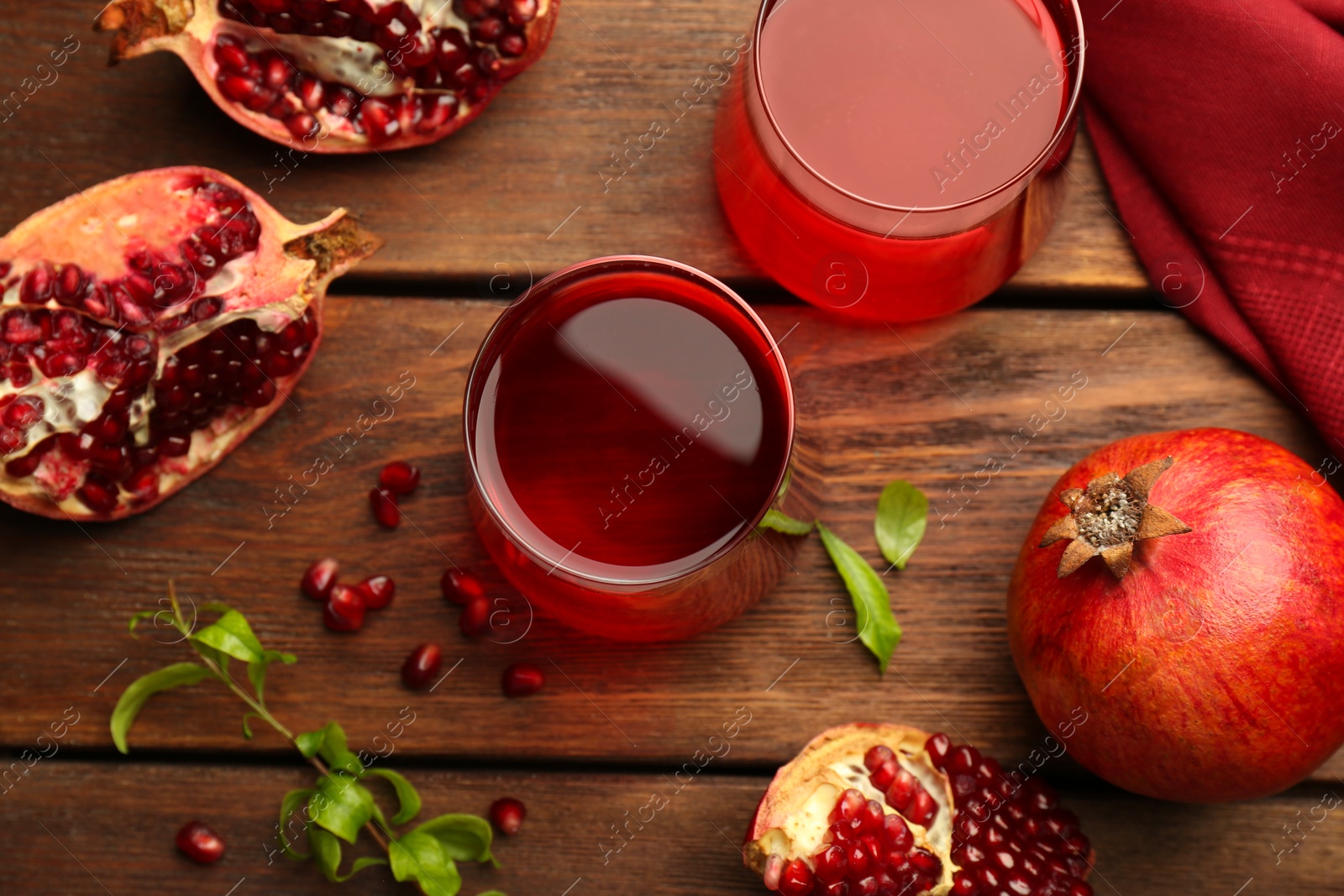 Photo of Tasty pomegranate juice in glasses and fresh fruits on wooden table, flat lay