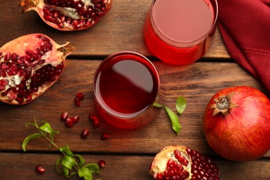 Photo of Tasty pomegranate juice in glasses and fresh fruits on wooden table, flat lay
