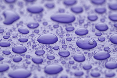 Photo of Water drops on lilac background, closeup view