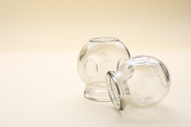 Photo of Glass cups on beige background, space for text. Cupping therapy