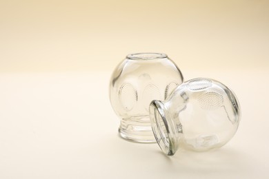 Glass cups on beige background, space for text. Cupping therapy