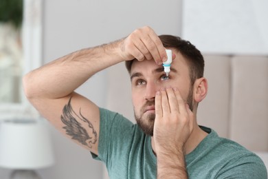 Photo of Young man using eye drops in room