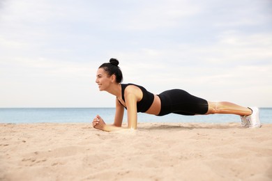 Image of Digital composite of highlighted bones and woman doing plank exercise on beach