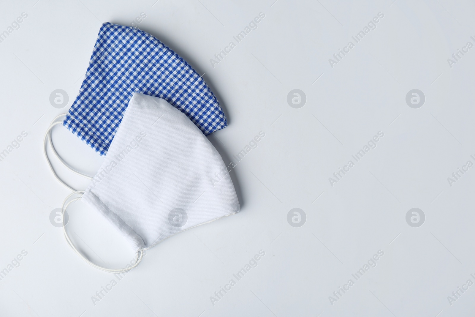 Photo of Homemade protective face masks on white background, top view. Space for text