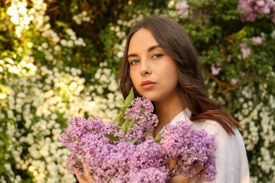 Attractive young woman with lilac flowers outdoors