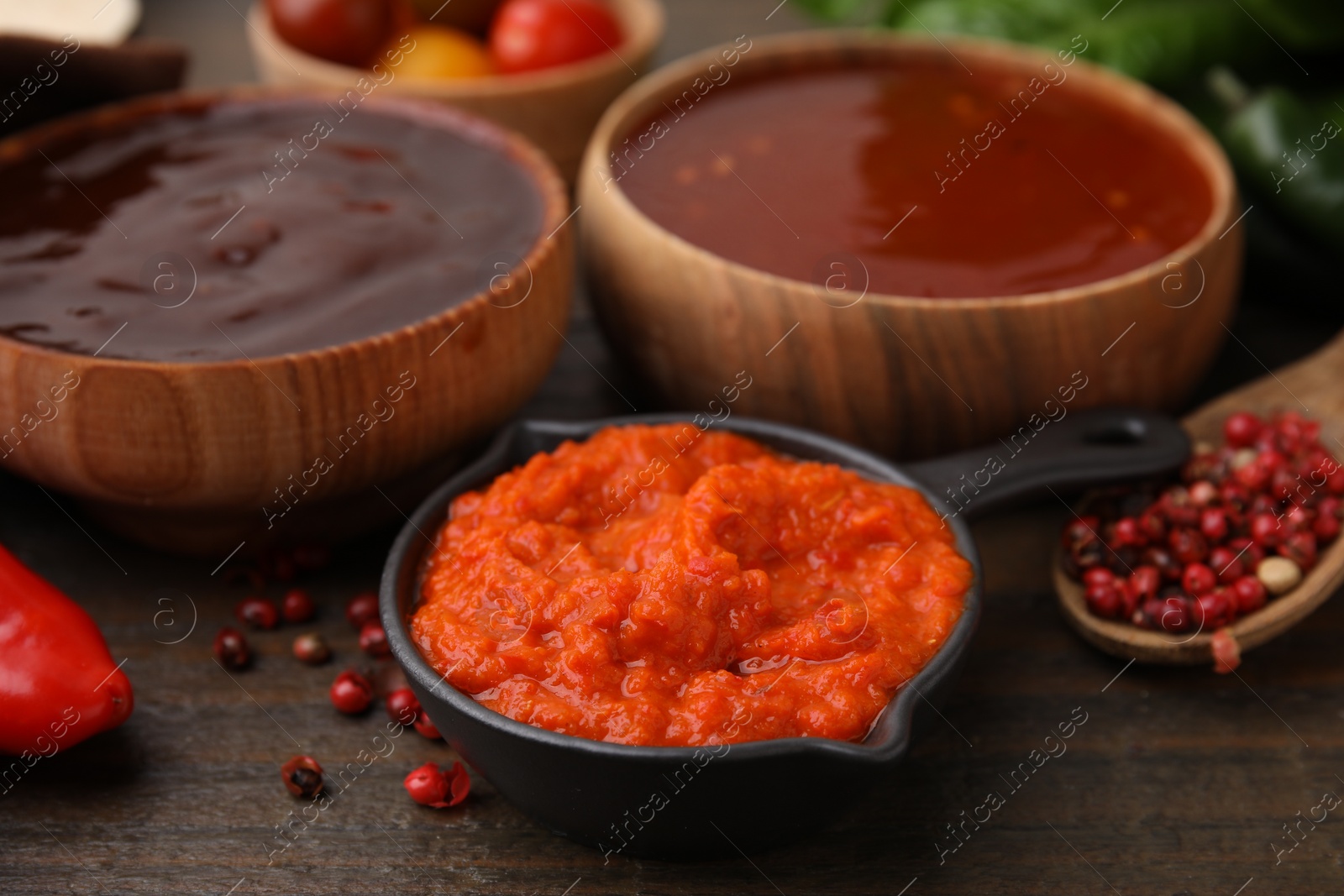 Photo of Different marinades and products on wooden table, closeup view