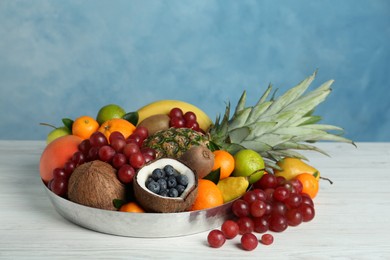 Assortment of fresh exotic fruits on white wooden table against light blue background