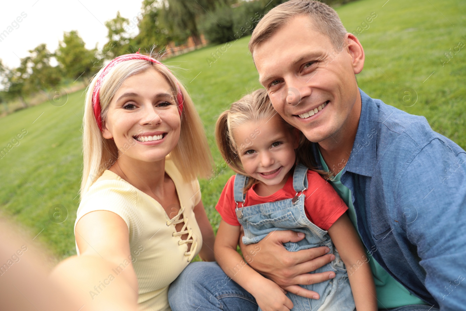 Photo of Happy family taking selfie in park on summer day