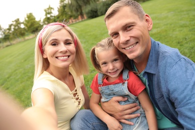 Happy family taking selfie in park on summer day