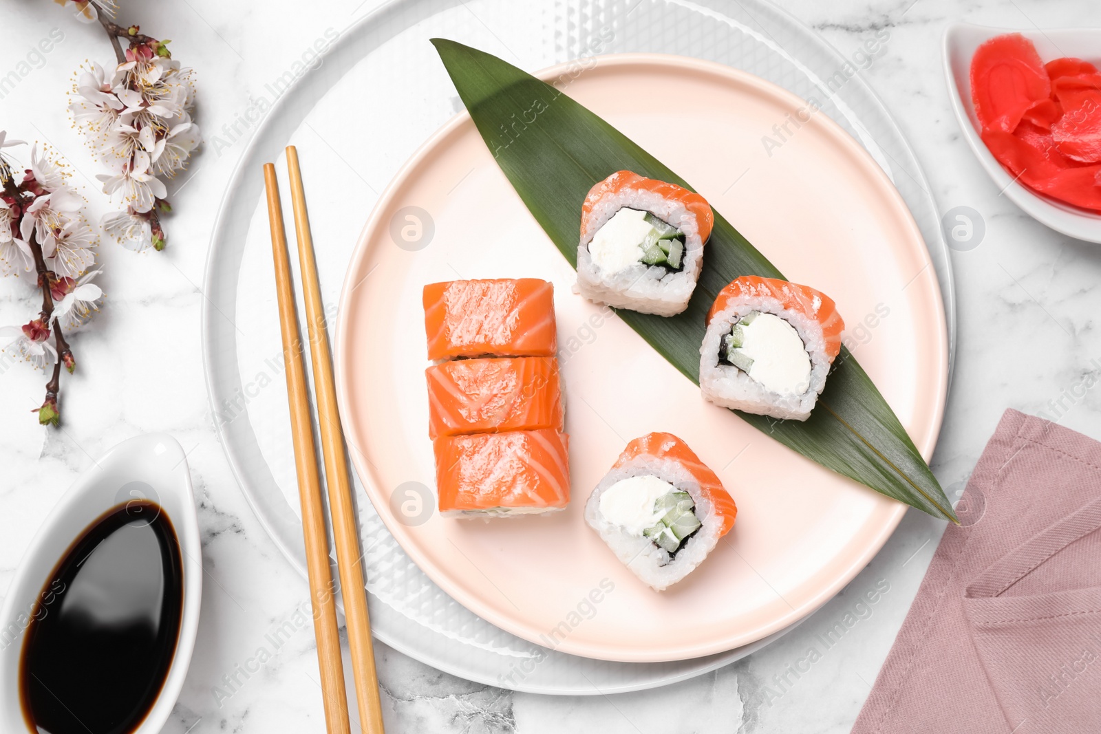 Photo of Tasty sushi rolls, soy sauce and ginger on white marble table, flat lay