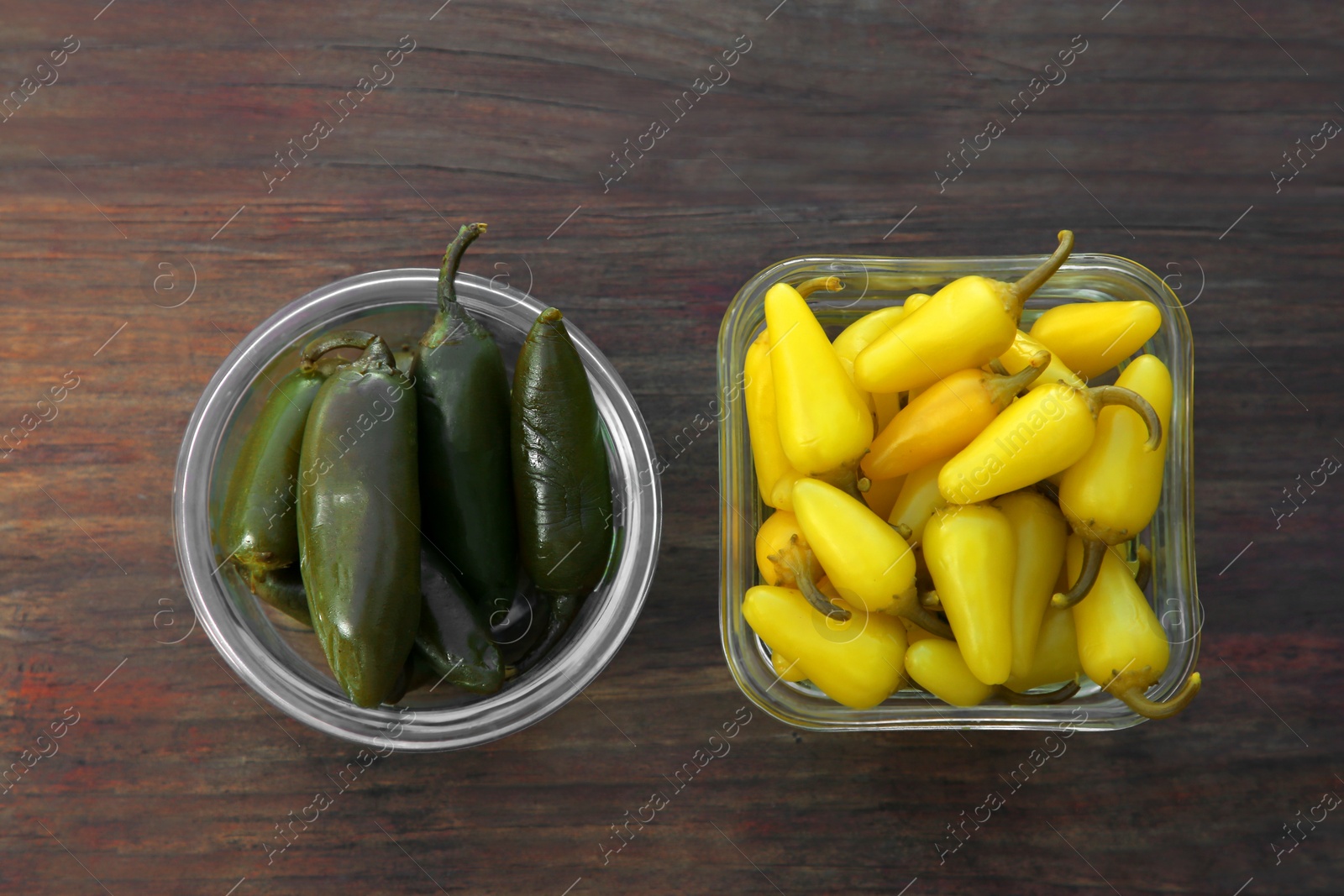 Photo of Pickled green and yellow jalapeno peppers on wooden table, flat lay