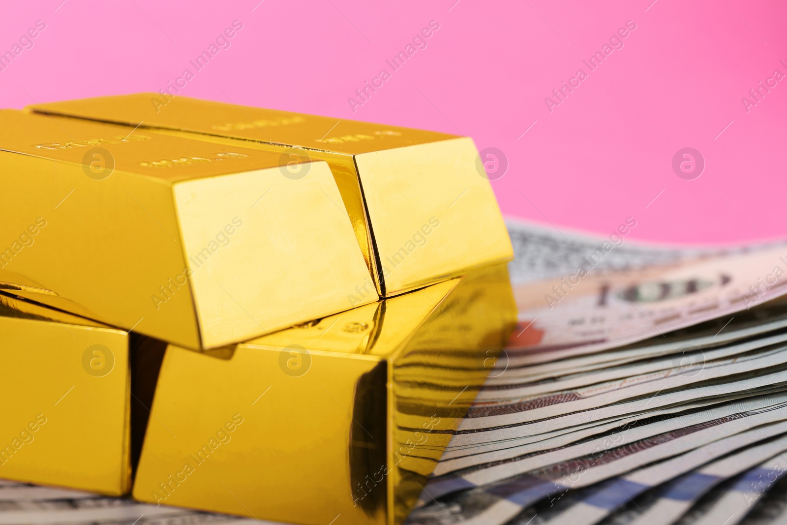 Photo of Shiny gold bars and dollar bills on color background