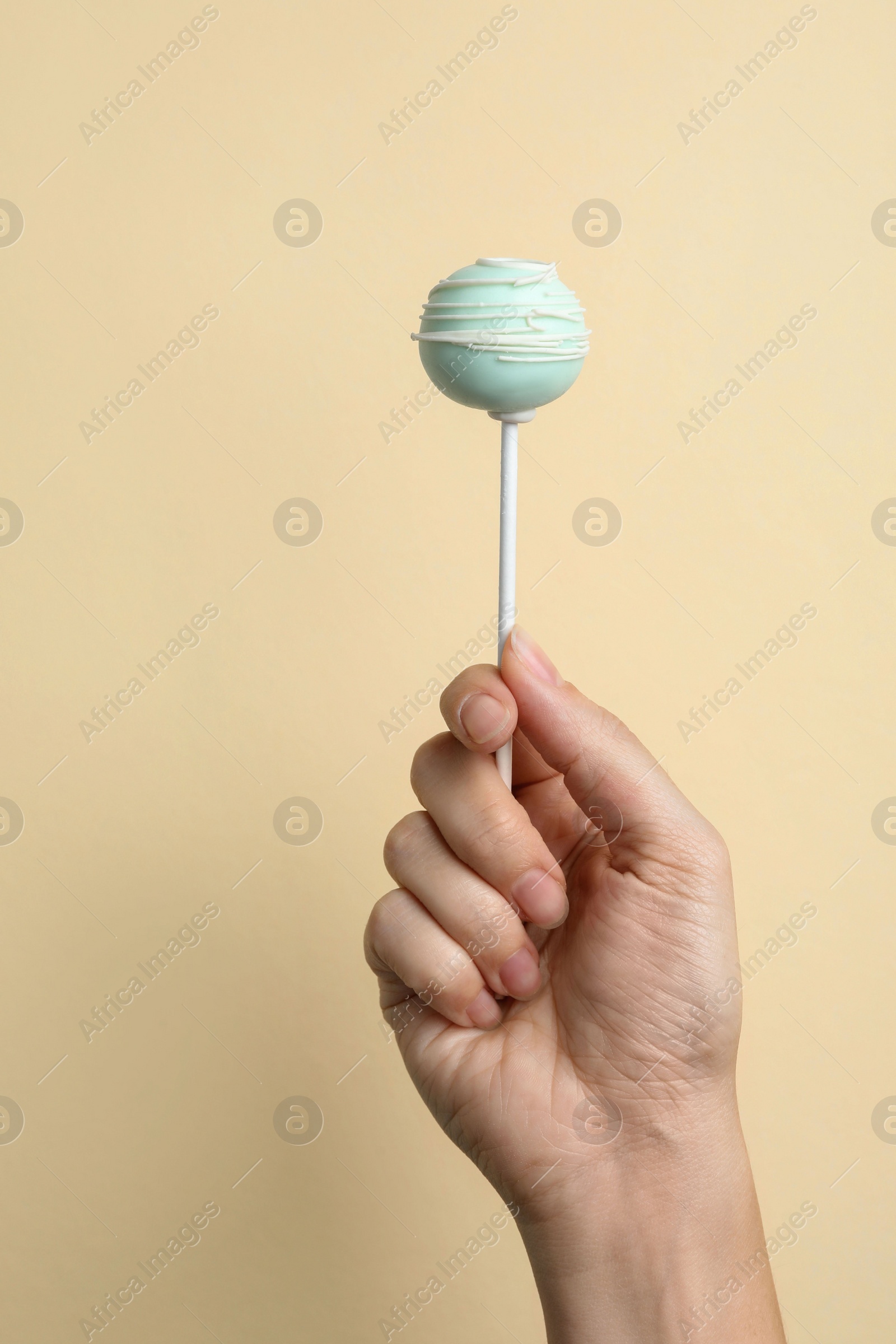 Photo of Woman holding sweet cake pop on light background, closeup