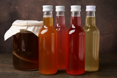 Photo of Delicious kombucha in glass bottles and jar on wooden table