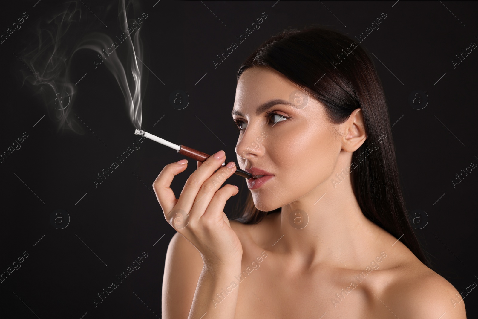 Photo of Woman using long cigarette holder for smoking on black background, space for text