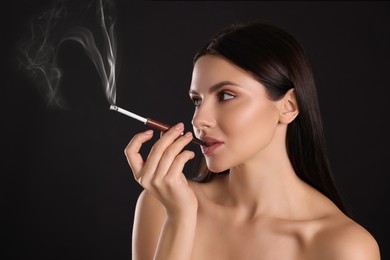 Woman using long cigarette holder for smoking on black background, space for text