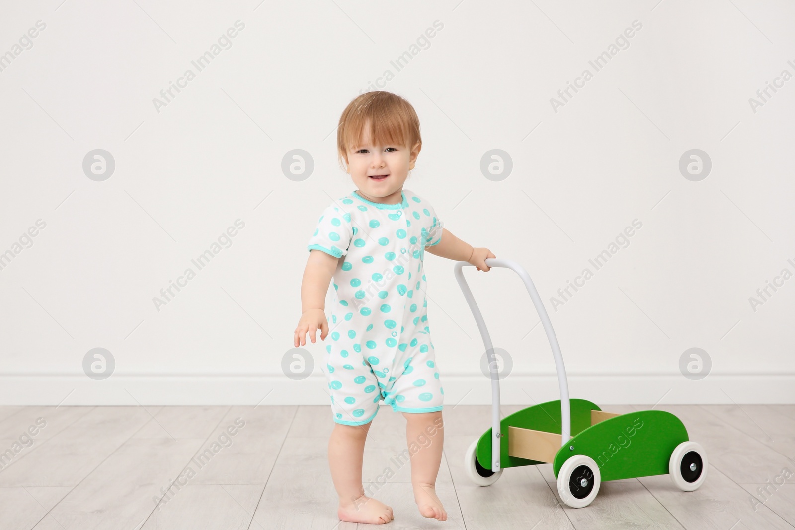 Photo of Cute baby playing with toy walker, indoors