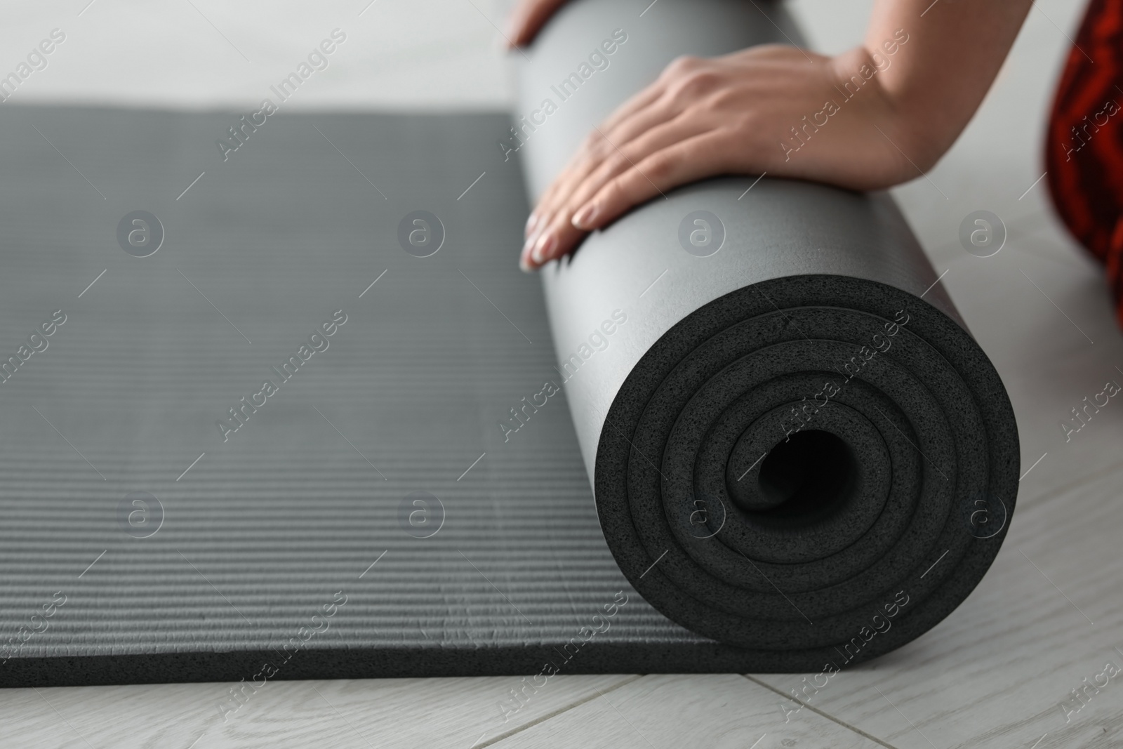 Photo of Young woman rolling yoga mat, closeup. Space for text