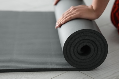 Photo of Young woman rolling yoga mat, closeup. Space for text