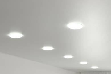 Photo of White ceiling with lamps indoors, below view