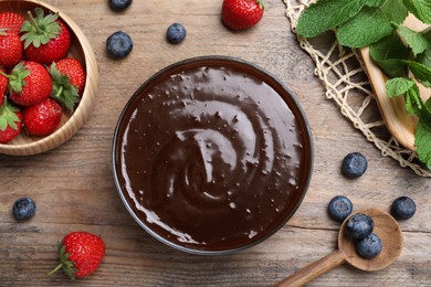 Photo of Delicious chocolate cream with berries and mint on wooden table, flat lay