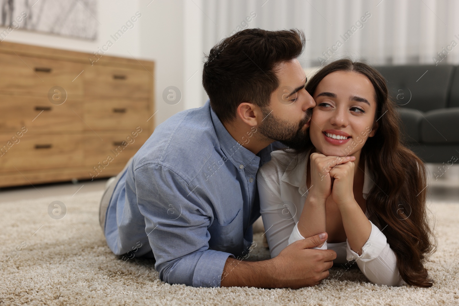 Photo of Young man kissing his girlfriend at home. Space for text