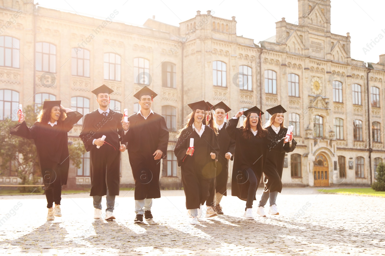 Photo of Happy students with diplomas outdoors. Graduation ceremony