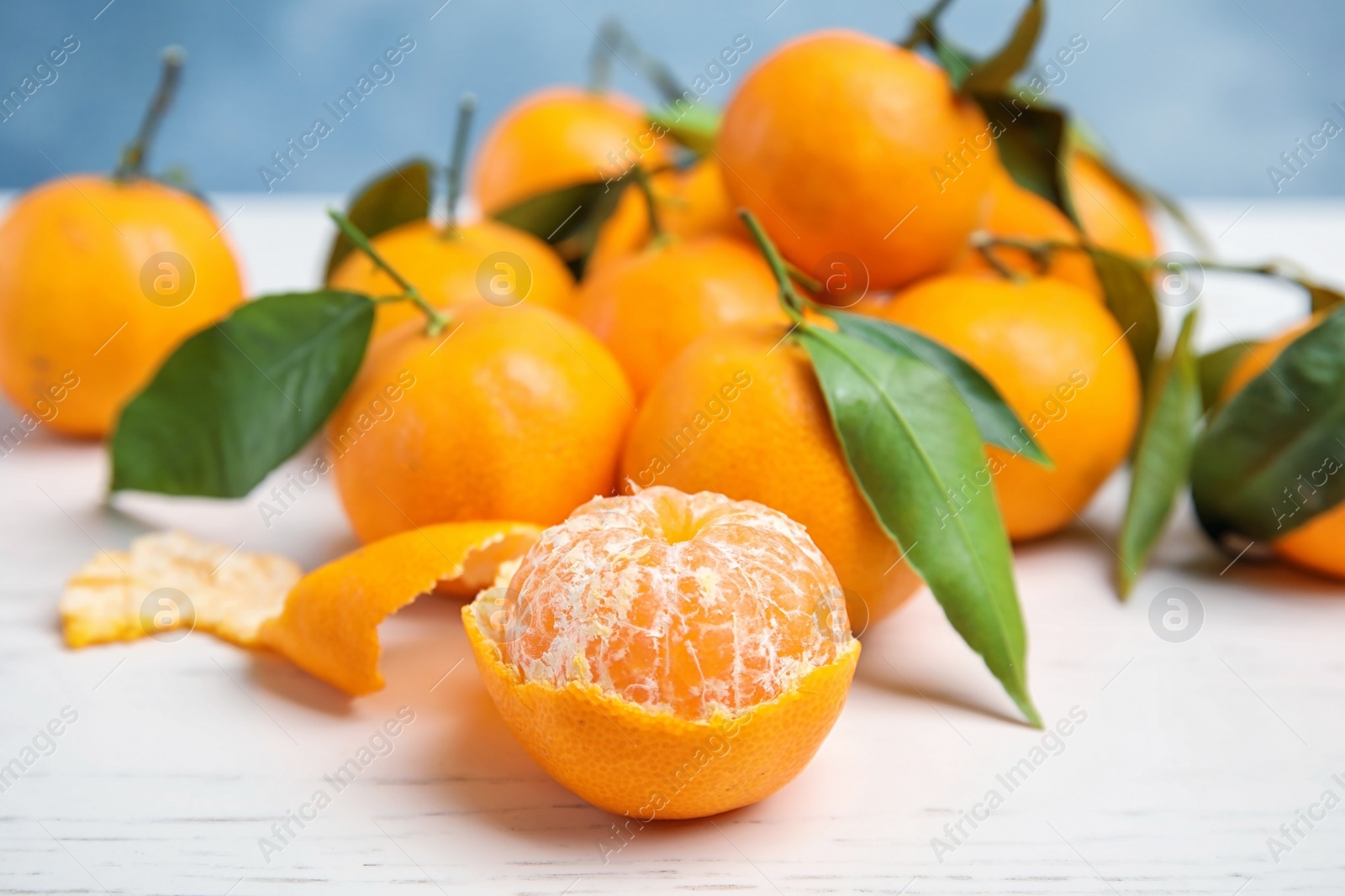 Photo of Fresh ripe tangerines with green leaves on table