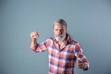 Handsome bearded mature man on color background