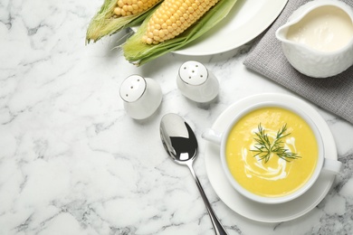 Photo of Delicious creamy corn soup served on white marble table, flat lay. Space for text