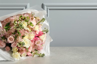 Beautiful bouquet of fresh flowers on table near grey wall, space for text