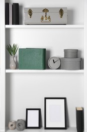 White shelves with clock, photo frames and different decor indoors. Interior design