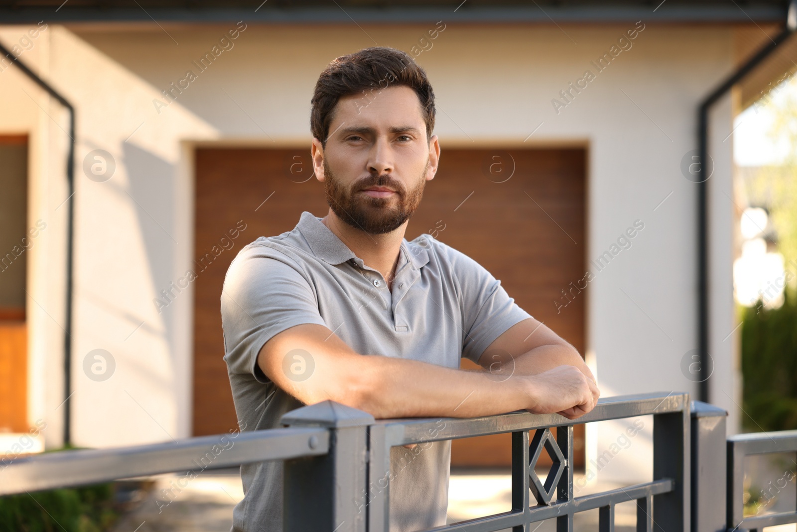 Photo of Portrait of serious neighbour leaning on fence outdoors