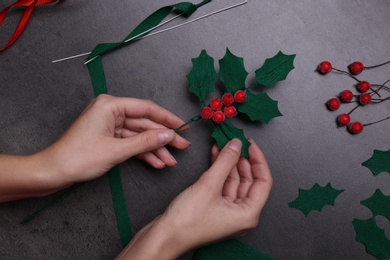 Photo of Woman making mistletoe branch on grey table, top view