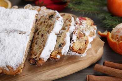 Photo of Traditional Christmas Stollen with icing sugar on wooden table, closeup